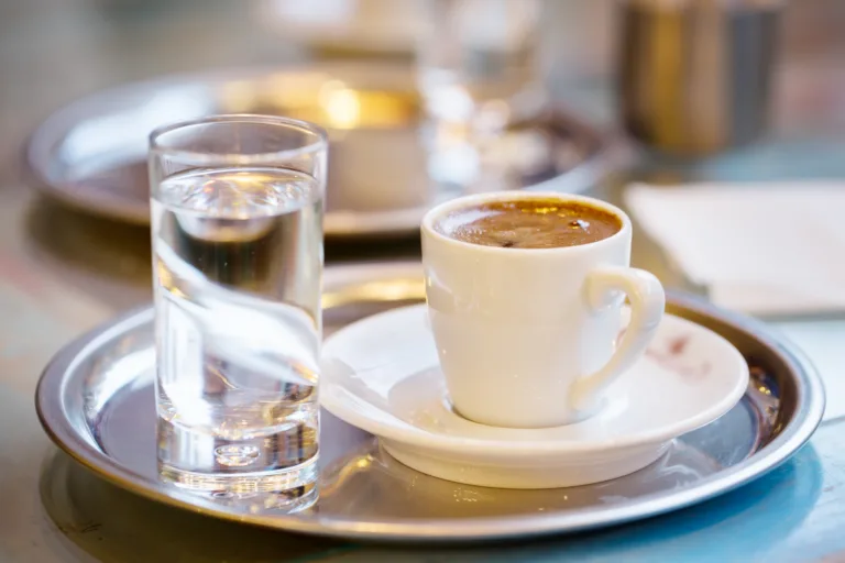 Cup of coffee and glass of water on cafe table