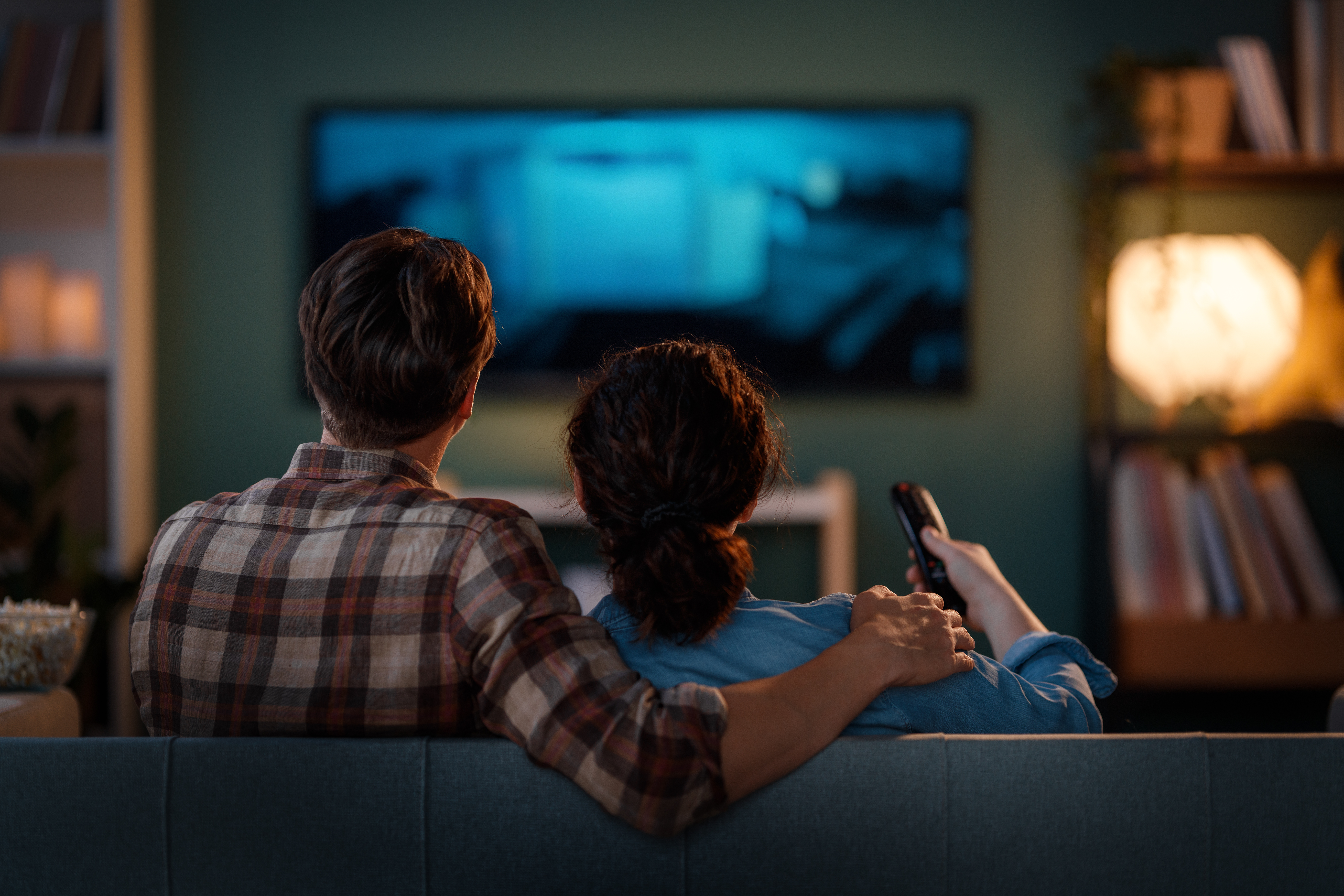 Happy family watching TV, movies in the evening at home. Couple spending time together.