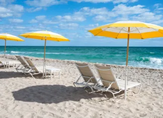 Dopust za 1.000 €? Na koncu vas lahko stane skoraj 2.000 € Luxury beach chairs and yellow umbrellas on white sand at the sea in Fort Lauderdale, Florida. No people.