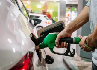 To so nove cene goriv: veljajo od jutri, znano koliko bomo odšteli za liter Unrecognizable male putting fuel dispenser in tank while refueling vehicle on self service gas station. High quality photo