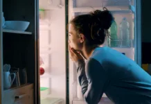 Večina Slovencev dela to napako: zaradi nje hladilnik poleti porabi precej več elektrike Woman looking in the fridge late at night, she is searching for a snack