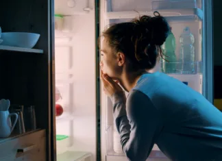Večina Slovencev dela to napako: zaradi nje hladilnik poleti porabi precej več elektrike Woman looking in the fridge late at night, she is searching for a snack
