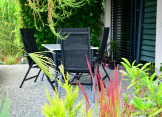 Pozabite na beton, ki razpoka, in prod, ki se raznaša: ta sodobna podlaga postaja prva izbira za dvorišča in dovoze Beautiful outdoor house patio with stone carpet flooring, growing green flowers and plants, and table with chairs. House terrace overgrown with plants with garden furniture.