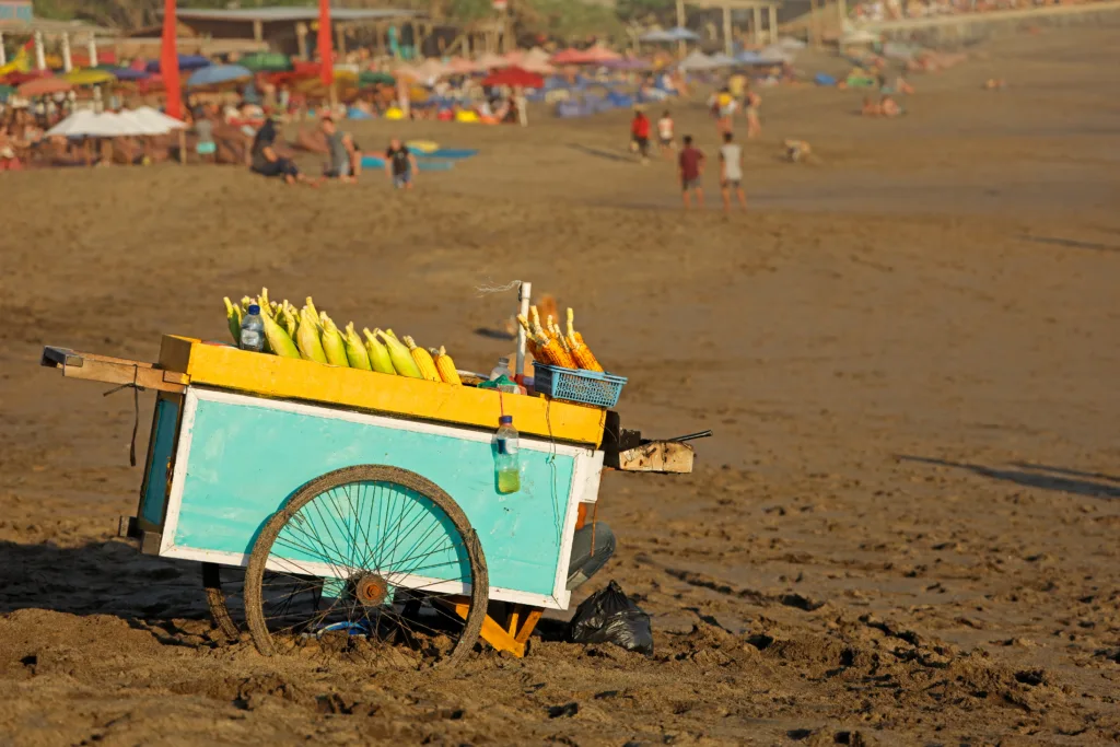 Cart of a street vendor with roasted corn for sale on a sandy beach - Bali, Indonesia