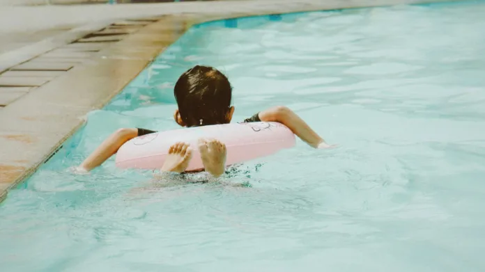 Child enjoying swimming with pink float in pool