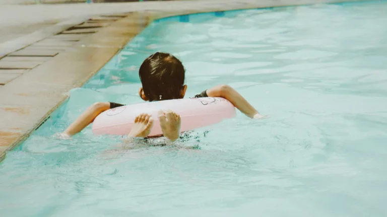 Child enjoying swimming with pink float in pool