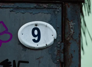 Ali veste, kaj predstavlja vaša hišna številka? Ena velja za nesrečno, druga pa za »zadetek na loteriji« Close-up of house number 9 on worn metal surface with rust, cracks and peeling paint. Urban grunge texture with industrial character, conveying age, decay and raw architectural detail.