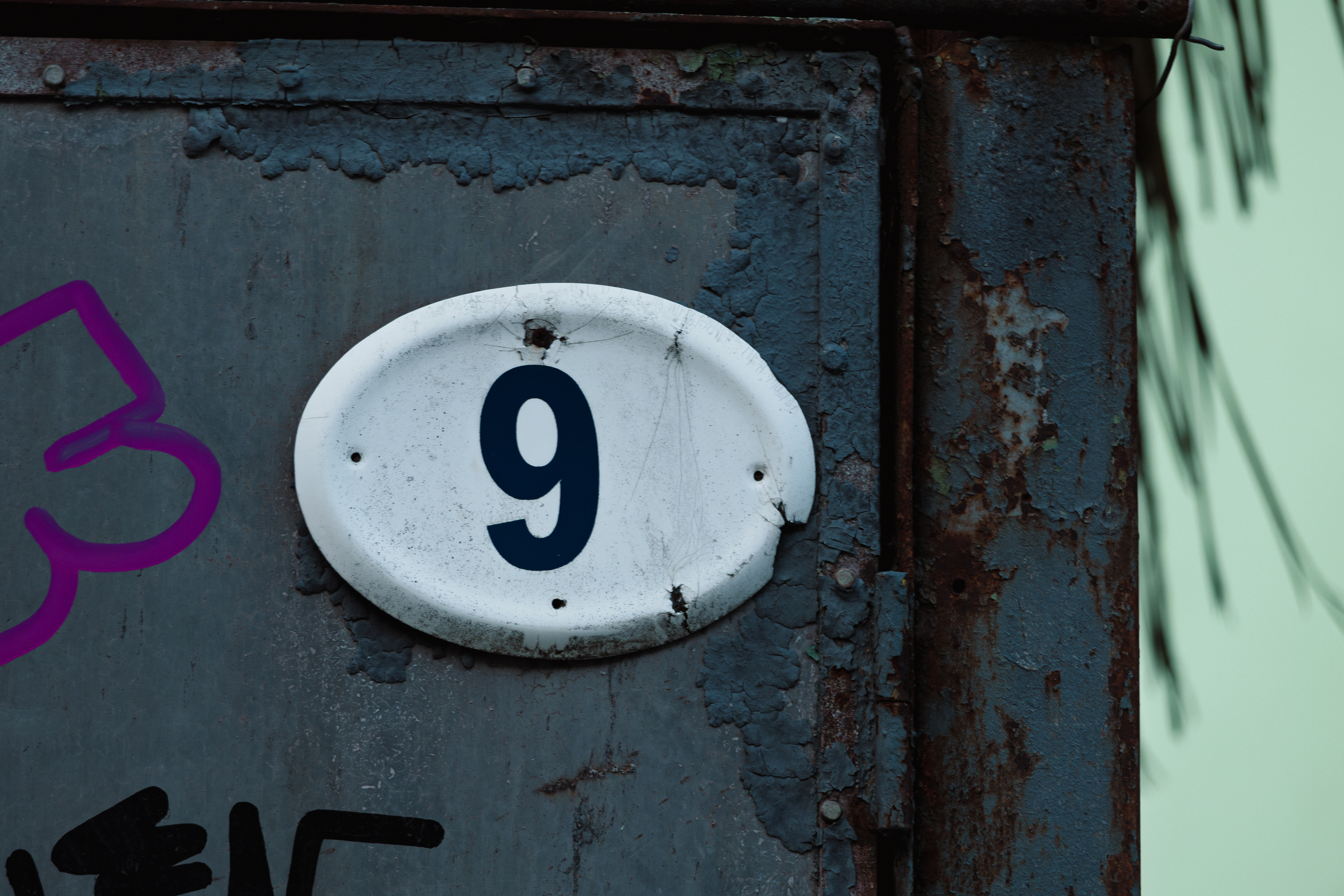 Ali veste, kaj predstavlja vaša hišna številka? Ena velja za nesrečno, druga pa za »zadetek na loteriji« Close-up of house number 9 on worn metal surface with rust, cracks and peeling paint. Urban grunge texture with industrial character, conveying age, decay and raw architectural detail.