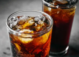 Kupujete Coca Colo, Fanto in Schweppes? Uf, ta navada vas na leto lahko stane več kot … Cola soft drink with ice cubes, Close up of soda fizzy drink in Cold glass on gray background