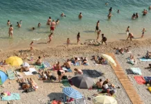 Dopustniki, vam na hrvaški plaži brisača čuva prostor? To pravijo pravila, na eni najlepših plaž pa so kazni visoke Dubrovnik, Croatia - July 06, 2021: A crowd of people resting on the beach near Old Town of Dubrovnik.