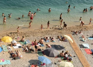 Dopustniki, vam na hrvaški plaži brisača čuva prostor? To pravijo pravila, na eni najlepših plaž pa so kazni visoke Dubrovnik, Croatia - July 06, 2021: A crowd of people resting on the beach near Old Town of Dubrovnik.