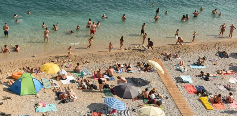 Dubrovnik, Croatia - July 06, 2021: A crowd of people resting on the beach near Old Town of Dubrovnik.