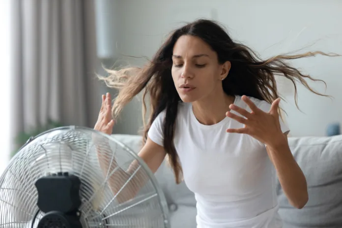 millennial-caucasian-girl-sit-on-sofa-in-living-room-breathe-fresh-air-from-floor-ventilator-suffer-from-summer-heat-at-home-young-woman-feel-hot-use-fan-at-home-struggle-with-lack-of-air-condition-stockpack-istock Millennial Caucasian girl sit on sofa in living room breathe fresh air from floor ventilator suffer from summer heat at home, young woman feel hot use fan at home struggle with lack of air condition