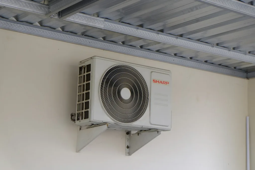 Outdoor air conditioning unit mounted on a wall, part of a home cooling and ventilation system commonly used in residential and commercial buildings.