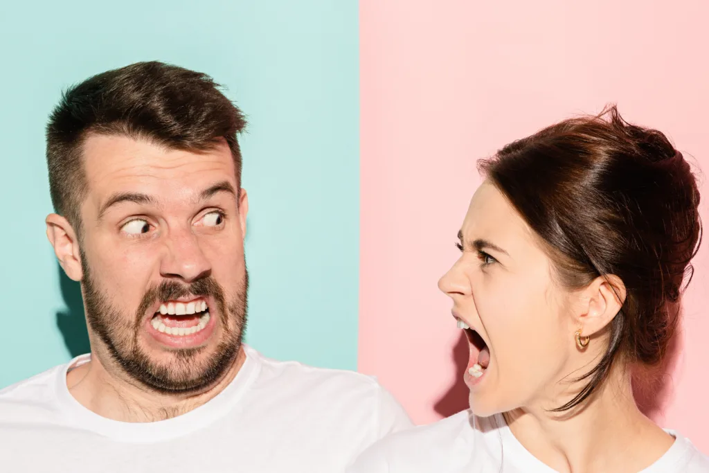 The attractive angry couple fighting and shouting at each other. quarrel concept. The studio shot on trendy pink and blue background. Human emotions concept