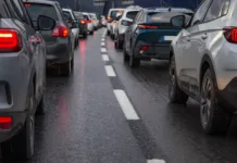Velika sprememba za voznike v EU v veljavi od torka: prinašamo podrobnosti novih pravil … Traffic jam with a row of cars on a highway during rush hour in the evening after work. red brake lights of stopped cars on the background of wet asphalt with white lanes at sunset
