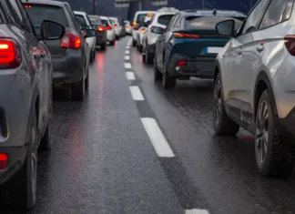 Velika sprememba za voznike v EU v veljavi od torka: prinašamo podrobnosti novih pravil … Traffic jam with a row of cars on a highway during rush hour in the evening after work. red brake lights of stopped cars on the background of wet asphalt with white lanes at sunset