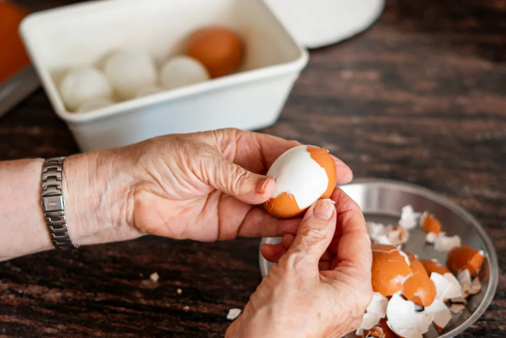 A person removes the shell from a boiled egg