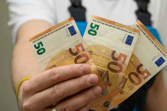 A worker in overalls showing banknotes in his hand, minimum wage for manual labor