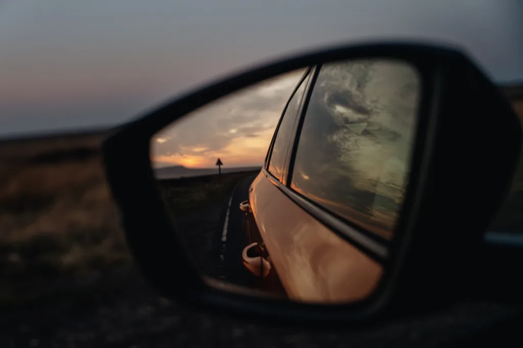 Beautiful sunset viewed in the rearview mirror while driving along a deserted road under a gentle evening sky