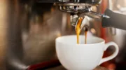 Closeup shot of an espresso maker pouring coffee into a cup inside of a cafe