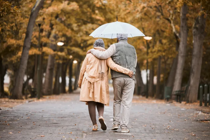 elderly-couple-walk-in-park-with-umbrella-and-fresh-air-outdoor-in-nature-in-fall-for-exercise-and-retirement-together-hug-love-and-care-with-trees-senior-man-and-woman-in-new-york-back-view-stockpack-istock Elderly, couple walk in park with umbrella and fresh air, outdoor in nature in fall for exercise and retirement together. Hug, love and care with trees, senior man and woman in New York back view.