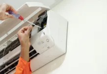 Teh zvokov iz klimatske naprave nikar ne ignorirajte: lahko so alarm za resne težave Hands of technician using screwdriver when installing air conditioner in bedroom of customer
