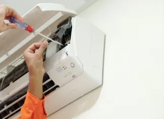 Teh zvokov iz klimatske naprave nikar ne ignorirajte: lahko so alarm za resne težave Hands of technician using screwdriver when installing air conditioner in bedroom of customer