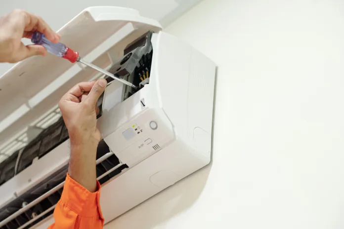 Hands of technician using screwdriver when installing air conditioner in bedroom of customer