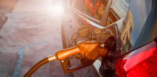 Pumping gas at gas pump. Closeup of man pumping gasoline fuel in car at gas station.