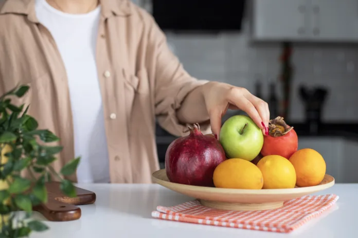 Woman taking apple from fruit bowl