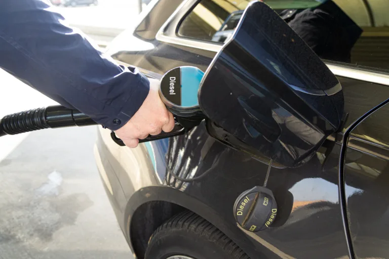 A man at a gas station is refueling a diesel car with diesel fuel.
