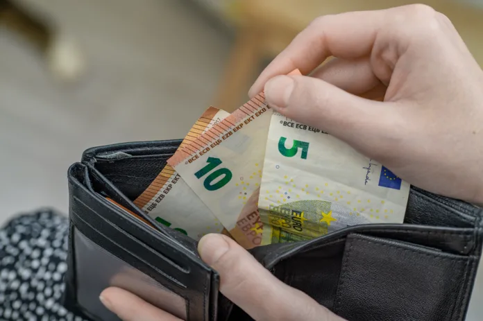 a-woman-takes-out-paper-euro-banknotes-from-her-wallet-stockpack-istock A woman takes out paper euro banknotes from her wallet