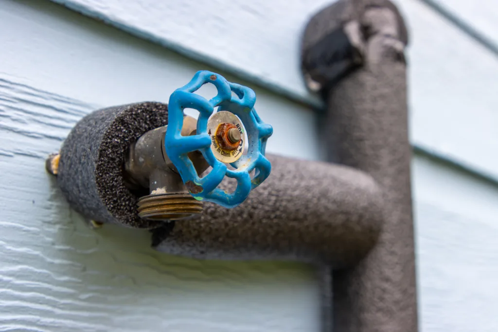An outdoor water spout and pipe wrapped in insulation to protect against freezing.
