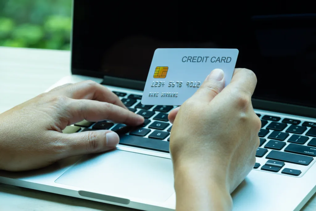 Hand of woman holding a credit card and typing on a laptop keyboard for online shopping, digital payment, and e-commerce and shopping online concept.