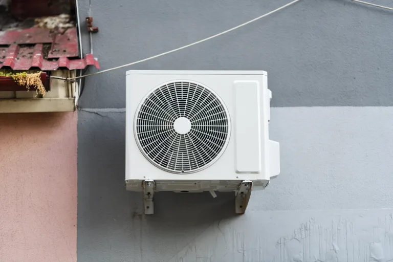The outdoor unit of a domestic split air conditioning system installed on the wall of a building.