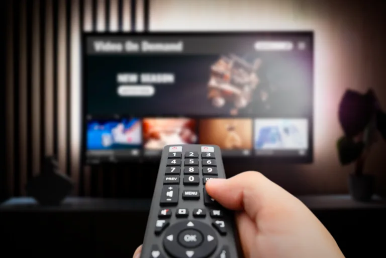 VOD service screen. Man watching TV with remote control in hand.
