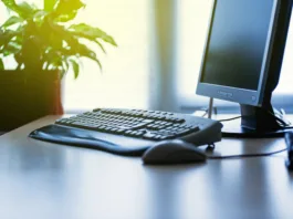 Personal computer on a desk in bright modern office lit by yellow sun coming from the window