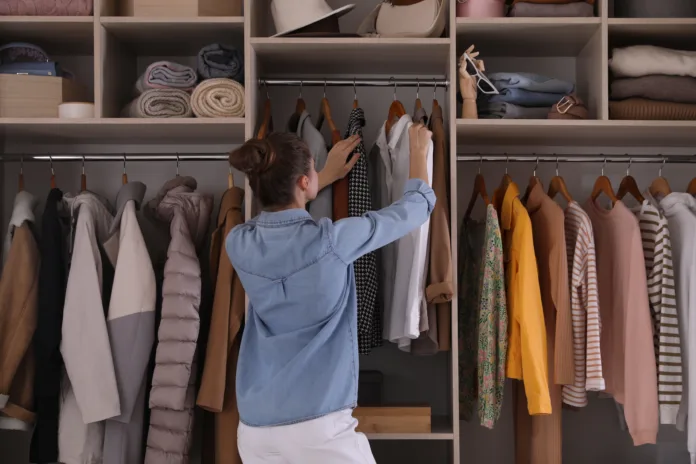 Young woman choosing clothes in wardrobe closet, back view